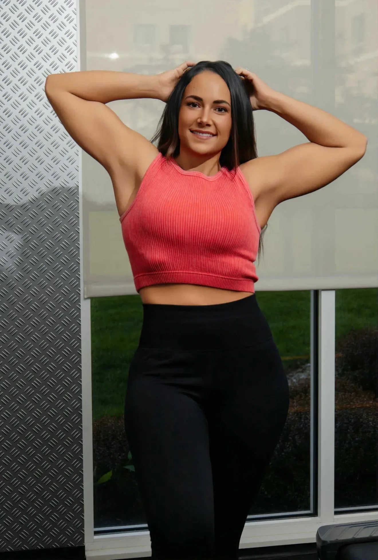 Audra Miller smiling in a pink athletic top and black leggings